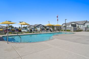 A swimming pool with yellow umbrellas in front of apartment buildings